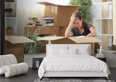 Sad evicted woman moving out packing boxes at home Wall mural