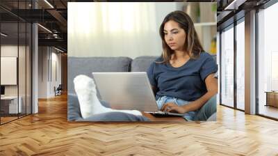 Serious desabled woman using a laptop at home Wall mural