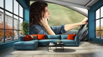 Side view of a woman driving a car and talking on the phone Wall mural