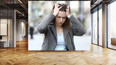 Stressed girl grabbing head complaining on city street Wall mural