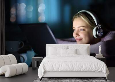 Teen wearing headphones watching media on laptop Wall mural