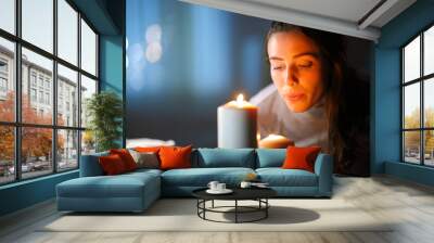 Woman blowing out candles at home in the night Wall mural