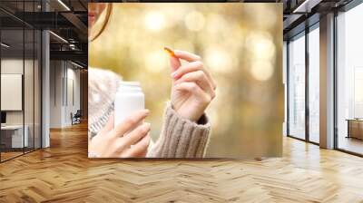 Woman hand holding a vitamin pill in autumn Wall mural