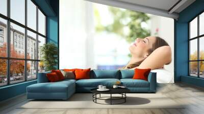 Woman relaxing lying on a couch at home Wall mural