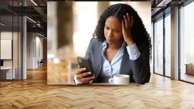 Worried businesswoman checking smart phone in a bar terrace Wall mural