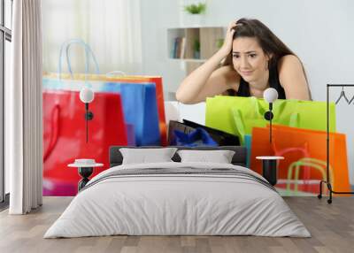 Worried shopaholic woman after multiple purchases Wall mural