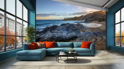 Sunset view of Minas Cove beach in Cabo Cope and Puntas de Calnegre Regional Park, with crystal clear water and rocks in the foreground Wall mural