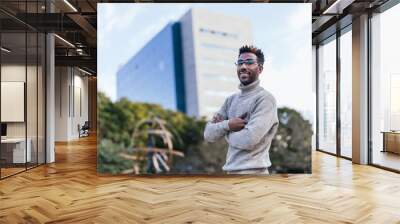 Young afro american man in turtleneck vest posing with arms crossed in a park Wall mural