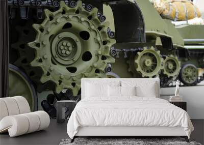 Tank tracks and steel wheels of heavy armored vehicles with green bodywork in row, military industry, modern army equipment, selective focus  Wall mural