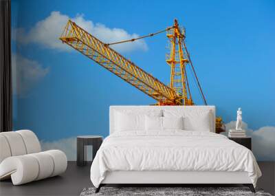 Yellow construction tower crane, heavy industry, blue sky and white clouds on background Wall mural