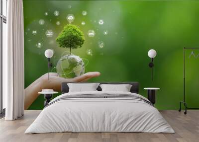 A hand is holding a globe with a tree growing on it. Several icons representing sustainability and environmentalism surround the tree. World environment day, ESG, co2, and net zero. green energy. Wall mural