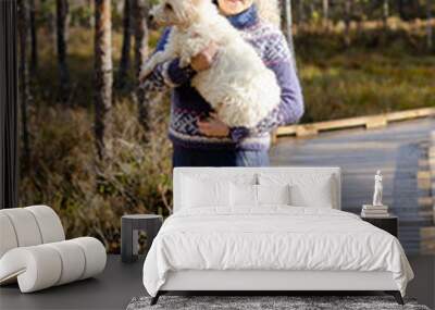 Woman with West Highland white terrier standing in autumn sun. Woman has Icenlandic pullover	
 Wall mural