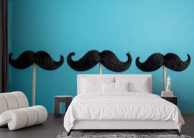 Black mustache on a stick, isolated on blue background, funny men's health day party prop Wall mural