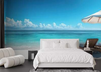 A panoramic view of the pristine white sandy beach, with two wooden sun loungers under an umbrella on one side and clear blue water stretching into the horizon. Wall mural