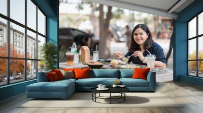 Asian woman eating healthy lunch at an outdoor restaurant during the day Relaxing urban lifestyle on weekends Wall mural