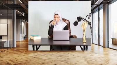 muslim business woman drinking water during working on laptop computer  Wall mural