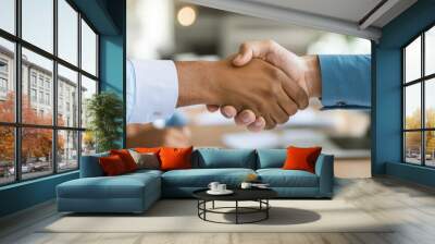 Two professionals shaking hands in an office setting, symbolizing successful partnership and trust. The environment reflects a diverse and collaborative business atmosphere, with a focus on growth. Wall mural