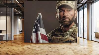 A military male soldier holding the USA flag, standing with a solemn expression Wall mural