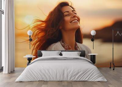 Portrait of calm happy smiling free woman with open arms and closed eyes enjoys a beautiful moment life on the seashore at sunset time Wall mural