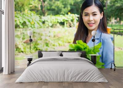 beautiful asian woman holding fresh green organic vegetable.teeth smile female gardeners stand in the vegetable farm. Wall mural