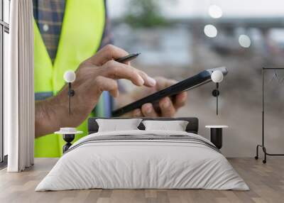 Close up construction worker holding pen touch screen using smartphone construction site outdoor Wall mural