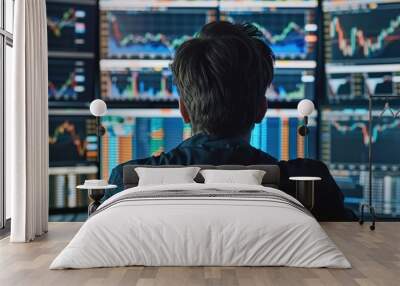 A financial analyst monitors multiple trading charts on several computer screens in a dimly lit office Wall mural