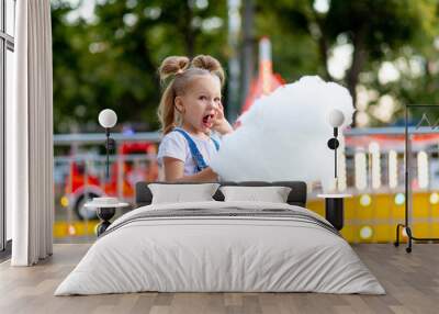 happy baby girl eating cotton candy at amusement Park in summer Wall mural