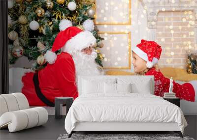 Santa Claus with a baby girl at the Christmas tree, new year and Christmas concept Wall mural