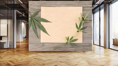 Hemp leaves and flowers with craft blank paper on old grunge wooden background. Top view. Minimalistic mockup. Wall mural