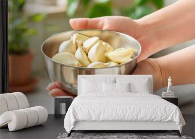 Hands holding a bowl of fresh garlic cloves in a kitchen Wall mural