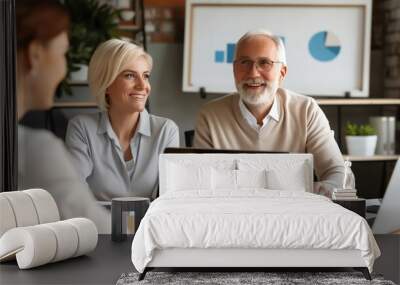 Smiling business team in a meeting, discussing graphs and charts on laptops in a modern office setting, showcasing teamwork and collaboration. Wall mural