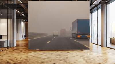 Truck or lorries and one van overtaking at a dangerous time with thick fog on a motorway in italy, europe. Wall mural