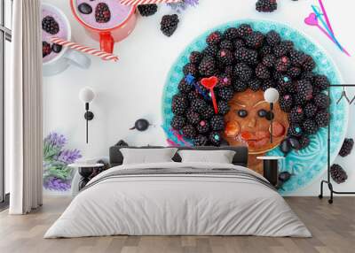 Funny culinary idea for children: edible African girl, face made of pancakes, gooseberries and blackberries, culinary art Wall mural