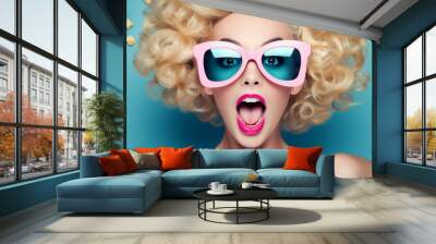 Portrait of happy young woman with curly blonde hair and pink retro sunglasses on blue background, banner Wall mural