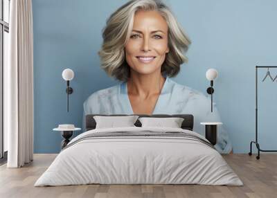 Portrait of smiling 50s tanned woman with long bob haircut in light blue blouse on blue background Wall mural