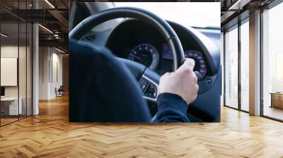 a young man is sitting at the wheel of a car, hand on the steering wheel. rear view of the dashboard Wall mural