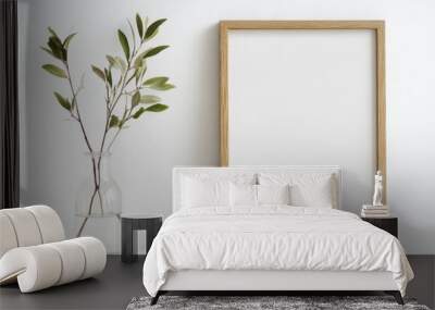 A minimalist wooden frame with blank canvas and a vase of greenery on a clean white table Wall mural