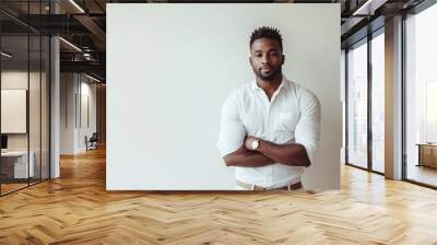 A stylish Black man confidently poses in a trendy casual outfit against a neutral background Wall mural