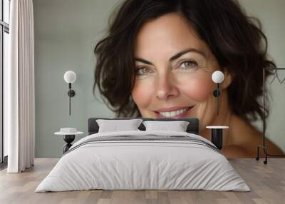 Close-up portrait of a smiling  mature woman with curly hair against a soft, neutral background Wall mural