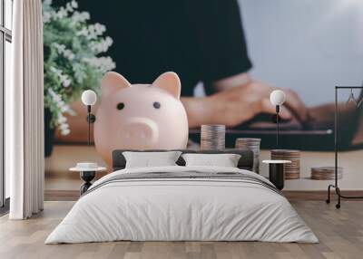 Saving money wealth and financial concept. Asian men working at home during the crisis are calculate family income and expenses, along with pension coins and piggy banks on wooden floors. Wall mural