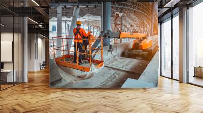  A Engineer wearing safety uniform and safety helmet ,controlling straight Boom Lift to construction roof on sky rail train platform station . Wall mural