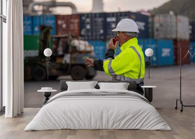 Engineer or worker standing forklift or truck vehicle are holding detail and appear to be discussing or reviewing documents, likely related to inspect about factory and industry worksite. Wall mural