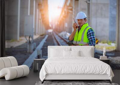 Portrait engineer under inspection and checking construction process railway and checking work on railroad station .Engineer wearing safety uniform and safety helmet in work. Wall mural