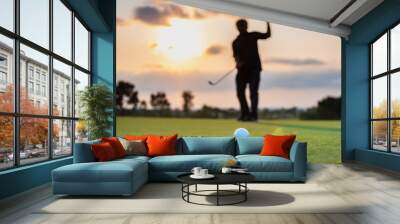 Silhouette golfer showing happiness when win in game , white golf ball on green grass of golf course with blur background. Wall mural