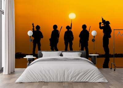 The military silhouettes of soldiers hold gun against with sunset sky background. Wall mural