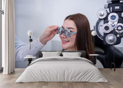 Woman optical shop customer doing eyesight measurement with optical phoropter check eye distance for eyeglasses is optical eye shop service.	 Wall mural