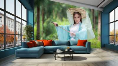 Young beautiful Asian woman wear dressing in traditional Chinese costume ancient fashion style warrior style with ancient word on in nature outdoor with green nature of park background. Wall mural