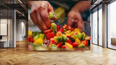 Close-up of hands adding fruit to a bowl of fruit salad Wall mural