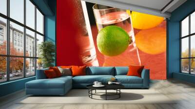 A glass of water stands on the table and green and yellow lemon. Wall mural