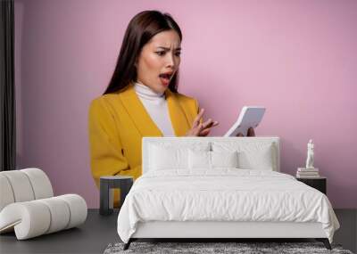 A woman in a yellow jacket is looking at a small white device Wall mural